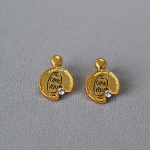 Macro view of gold irregular earrings with Olive You engraving and zircon accents