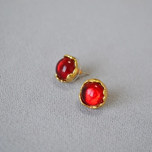 Close-up of vintage red gemstone earrings with irregular gold bud texture on fabric