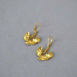 Artistic layered ginkgo leaf drop earrings in vintage gold plated brass on grey fabric