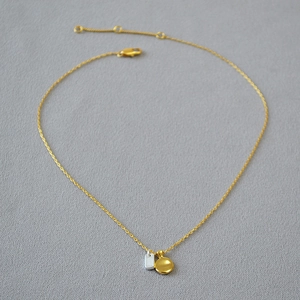 Detail of brass gold-plated necklace with mixed silver frosted and gold mirror pendants