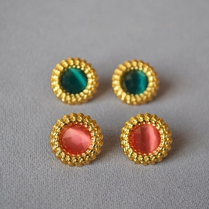 Détail de boucles d'oreilles vintage dorées avec bordure torsadée et pierres colorées