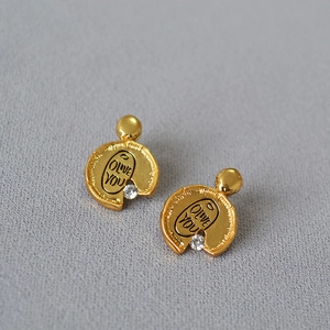 Macro detail of gold-plated irregular earrings with zircon stone and Olive You engraving