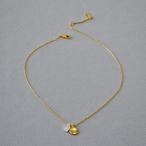 Detailed close-up of a gold chain necklace with round gold and silver rectangular pendants