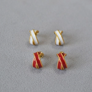 Detail of vintage C-shape twisted ribbon earrings with enamel finish and gold bead trim