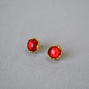 Detail of vintage red gemstone earrings with golden wavy metallic texture and retro style