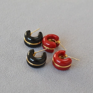 Detail of minimalist C-shaped hoop earrings in red and black with gold metallic trim