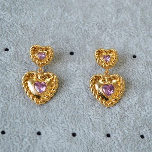 Macro detail of gold-plated twisted edge earrings with double pink heart-shaped stones