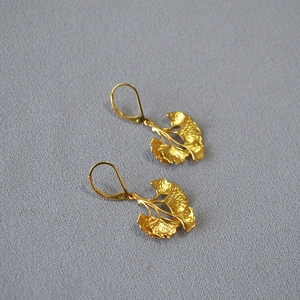 Detailed view of golden ginkgo leaf earrings with lever-back closures and realistic textures