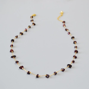 Close-up of garnet stone necklace with gold chain, lobster clasp, and extension