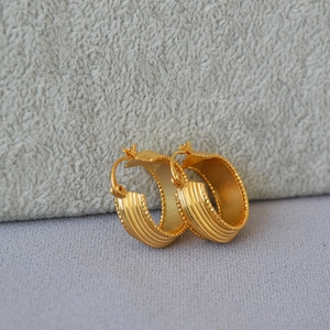 Detail of vintage gold plated brass earrings with vertical stripes and beaded edges