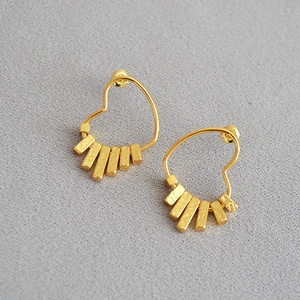 Detail view of gold-plated heart drop earrings with unique hammered metal texture bars