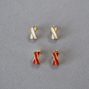 Detail of red and white enamel crisscross C-shaped stud earrings with gold beaded edges