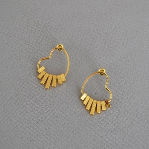Detailed macro view of heart shaped gold earrings with hand hammered metallic textures