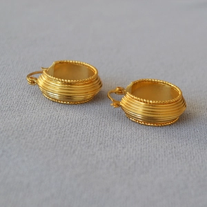 Detail of vintage ribbed gold earrings with textured beaded edges and a polished finish
