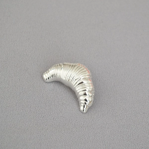Modern silver irregular croissant horn brooch with a polished metallic texture and ribbed design
