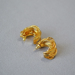 French retro gold multi-layer irregular twisted hoop earrings on grey textured fabric