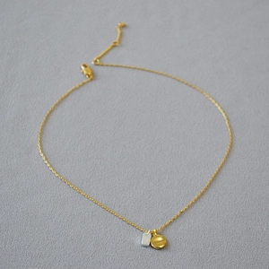 Detail of minimalist gold chain necklace with geometric square and round metal charms