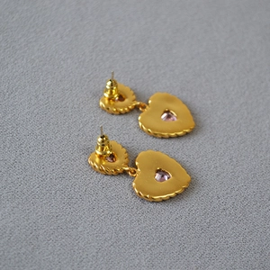 Macro detail of gold plated heart earrings showing back craftsmanship and silver needles