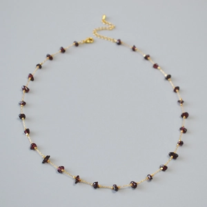 Close-up of gold chain necklace featuring irregular red garnet stones and lobster clasp