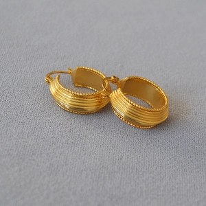 Detail of vintage gold-plated hoop earrings with vertical ridges and milgrain texture