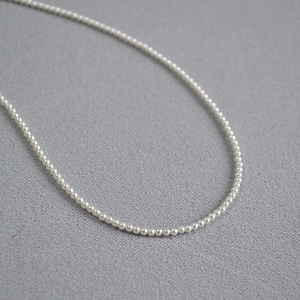 Vue macro d'un collier de perles blanches fines à haute brillance avec courbe en U