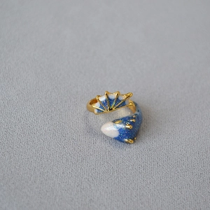 Detailed view of adjustable fish-shaped ring with blue glitter enamel and gold trim