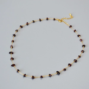 Detail of garnet gemstone necklace with irregular deep red stones and golden bead chain