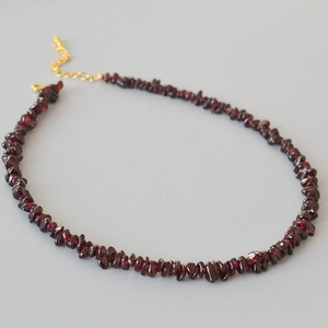 Détail macro d'un collier en perles de grenat avec fermoir mousqueton doré ajustable
