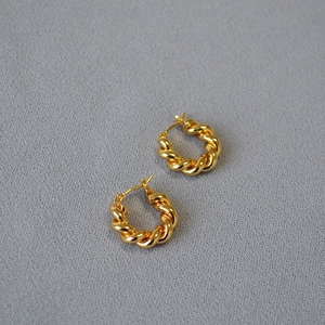 Vue rapprochée des boucles d'oreilles créoles torsadées dorées avec texture polie