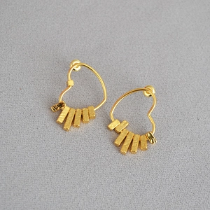 Gold-plated heart earrings with five hammered texture hanging bars on a grey fabric