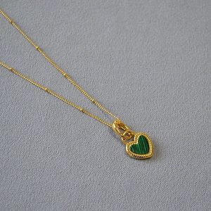 Détail de collier cœur doré avec pierre de malachite verte et bordure perlée