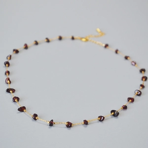 Close-up of garnet stones on a minimalist gold chain with lobster clasp and extender