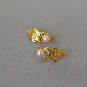 Vintage textured gold leaf earrings with round white pearls on a grey background