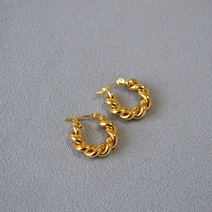 Vue détaillée de boucles d'oreilles créoles dorées avec un design de corde torsadée