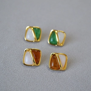 Detail view of retro geometric square stud earrings in green and amber color schemes