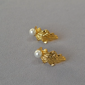Detail of golden oak leaf earrings with textured finish and glossy white pearls