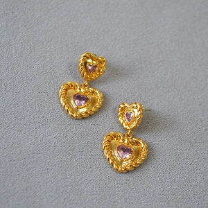 Detailed close-up of vintage heart earrings with pink zircon and twisted gold trim