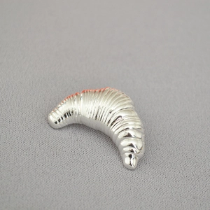 Macro shot of silver croissant-style irregular textured metallic brooch detail