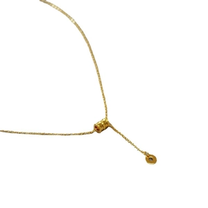 Collier minimaliste en laiton doré avec pendentif cylindrique sur fond blanc épuré