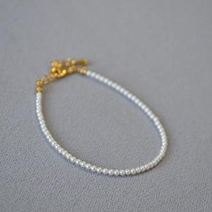 Détail d'un bracelet en perles de style français minimaliste avec un fermoir doré brillant