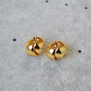 Macro shot of minimalist gold plated double C twist earrings with high polish finish