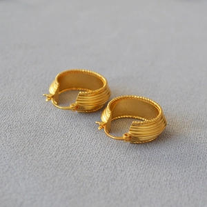 Macro detail of gold plated hoop earrings with ribbed texture and beaded edge design
