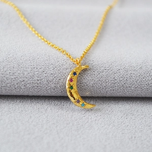 Macro view of gold crescent moon pendant with five multicolored stones and hammer texture