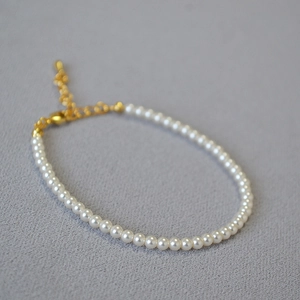 Détail d'un élégant bracelet en perles de 3mm avec fermoir mousqueton doré et chaîne d'extension