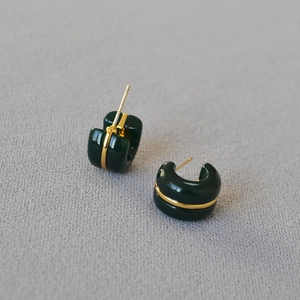 Detail of C-shaped resin hoop earrings in dark green with a gold metallic line inlay