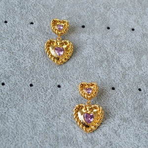 Macro detail of gold-plated brass heart earrings with purple zircon and twisted rope borders