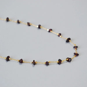 Macro shot of gold chain necklace with irregular deep red garnet stones and tiny beads