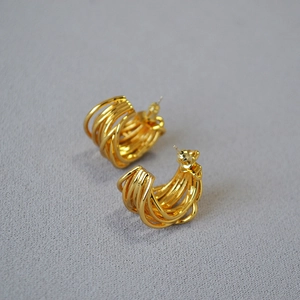 French retro gold-plated multi-layer irregular twisted C-shape hoop earrings on grey linen