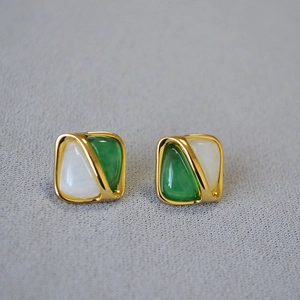 Macro detail of geometric square brass studs with white and emerald green resin inlays