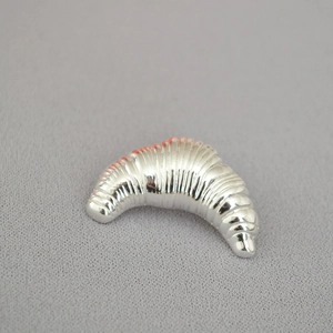 Macro view of silver croissant-shaped brooch with realistic textured metallic folds